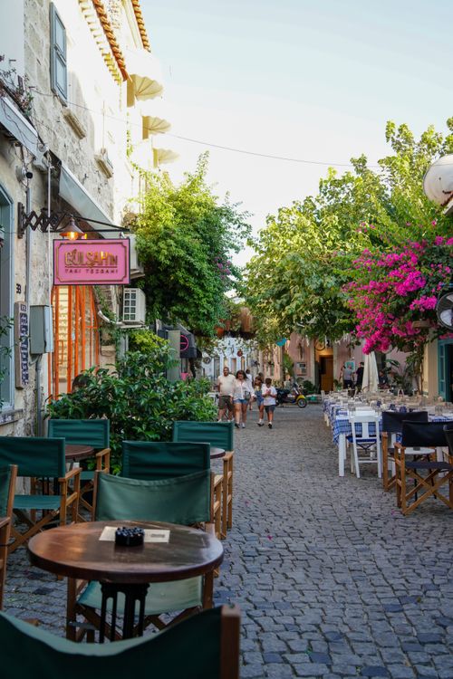 Free Picturesque European street scene with cafes, cobblestone path, and lush greenery. Stock Photo