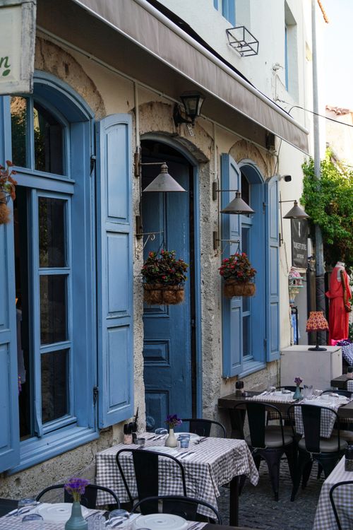 Free Cozy outdoor cafe with blue shutters and checkered tablecloths, perfect for a relaxed meal. Stock Photo