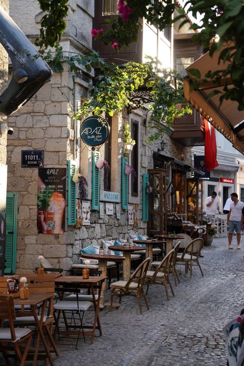 Free A quaint outdoor cafe on a cobblestone street featuring tables, shops, and vibrant decor. Stock Photo