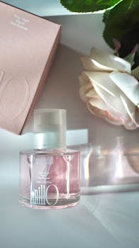 Stylish pink perfume bottle with rose and elegant packaging.