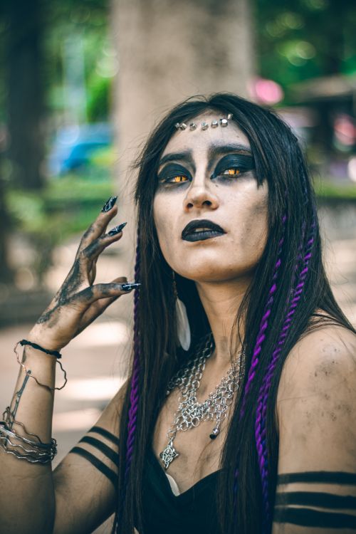 Free A woman with elaborate gothic makeup and purple hair extensions in a park setting in Mexico City. Stock Photo