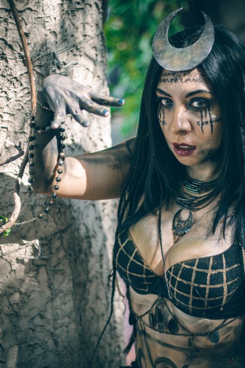 Free A woman with intricate, mystical makeup poses as a witch in an outdoor setting. Stock Photo