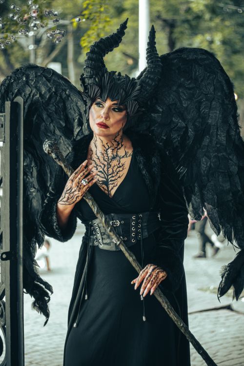 Free Mystical being in gothic attire with horns and black wings standing in an urban setting. Stock Photo
