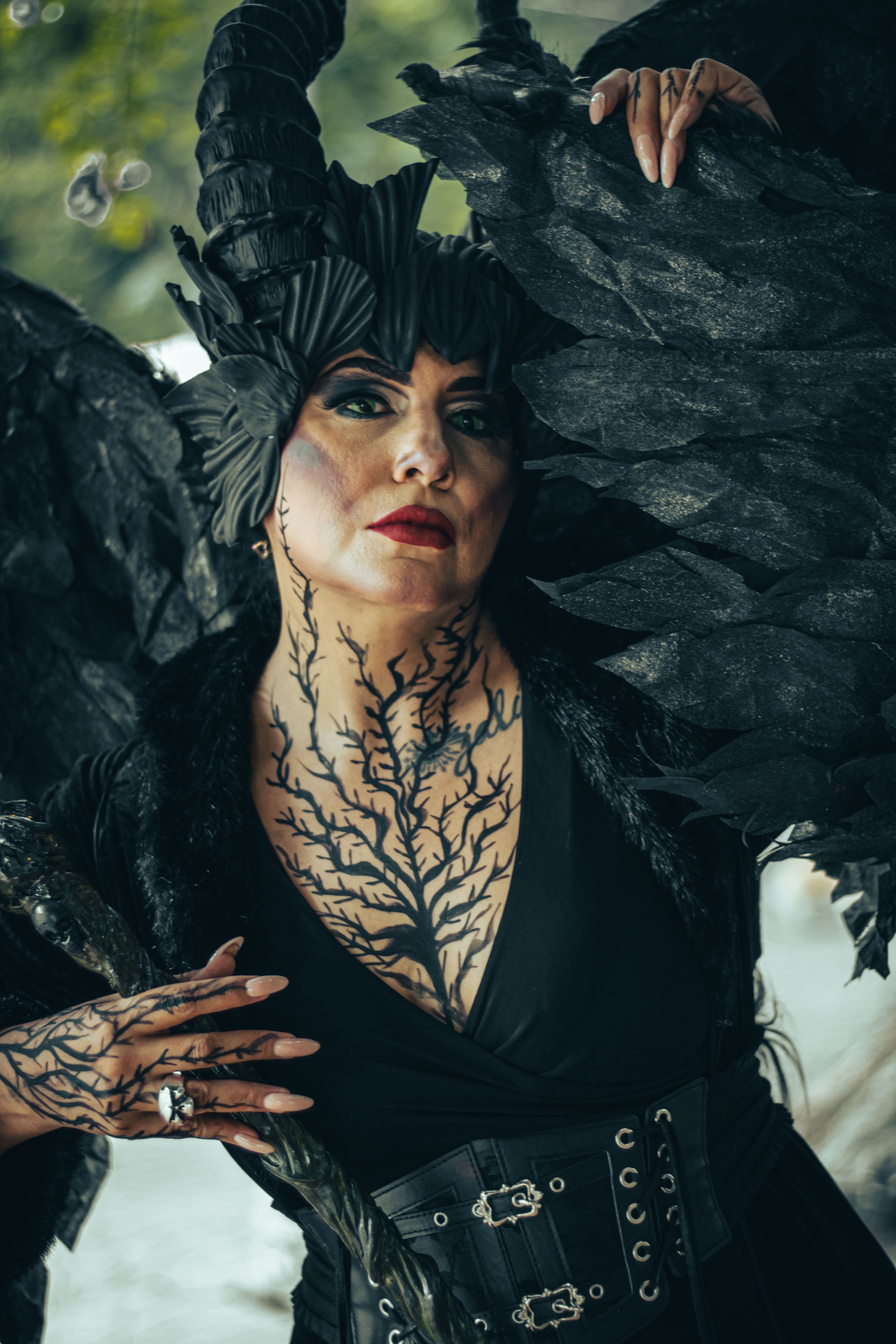 Portrait of a woman in dark, gothic fantasy makeup with black wings and horns.
