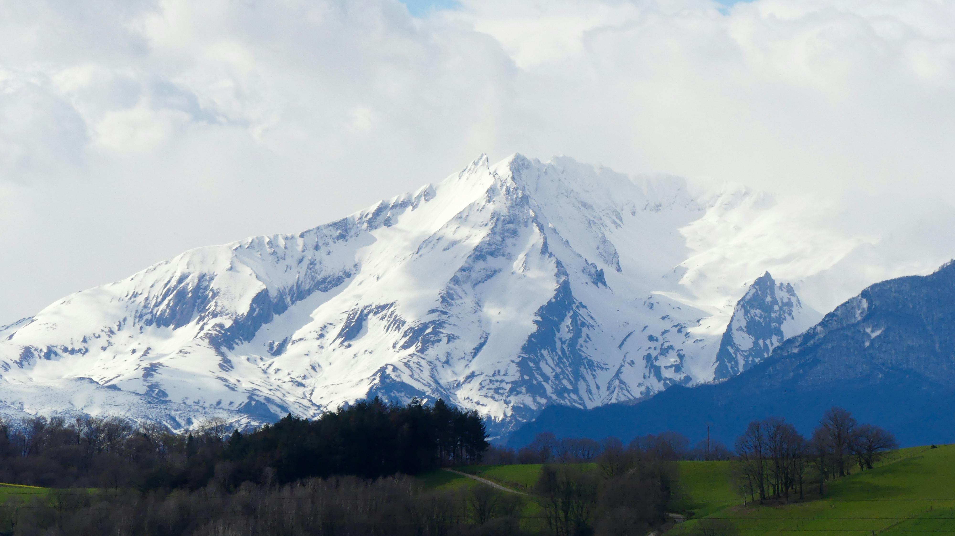 Spectacular view of a snow-capped mountain in the French Alps under a cloudy sky.