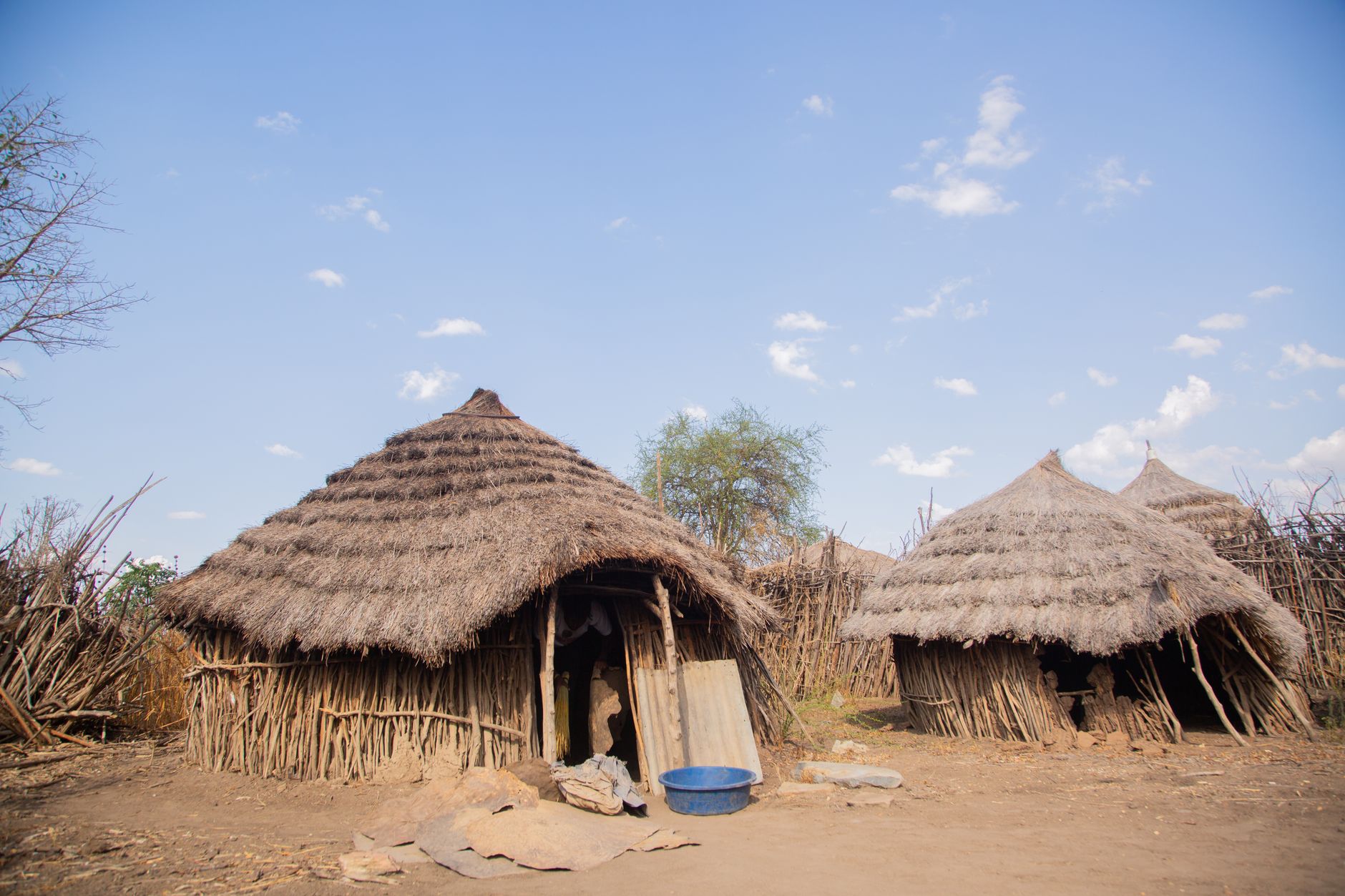 Rural African village with traditional grass huts under a clear blue sky.