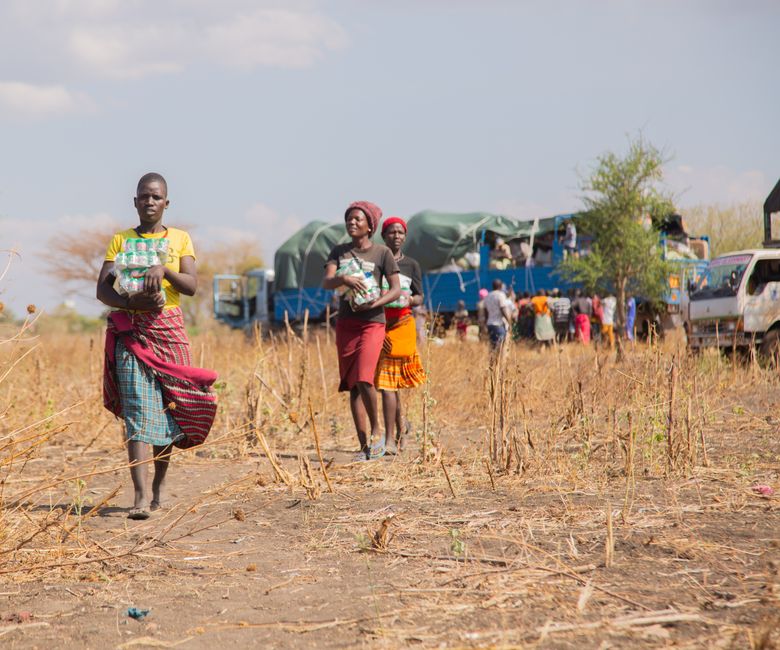 People receiving humanitarian aid in a rural area during daytime.