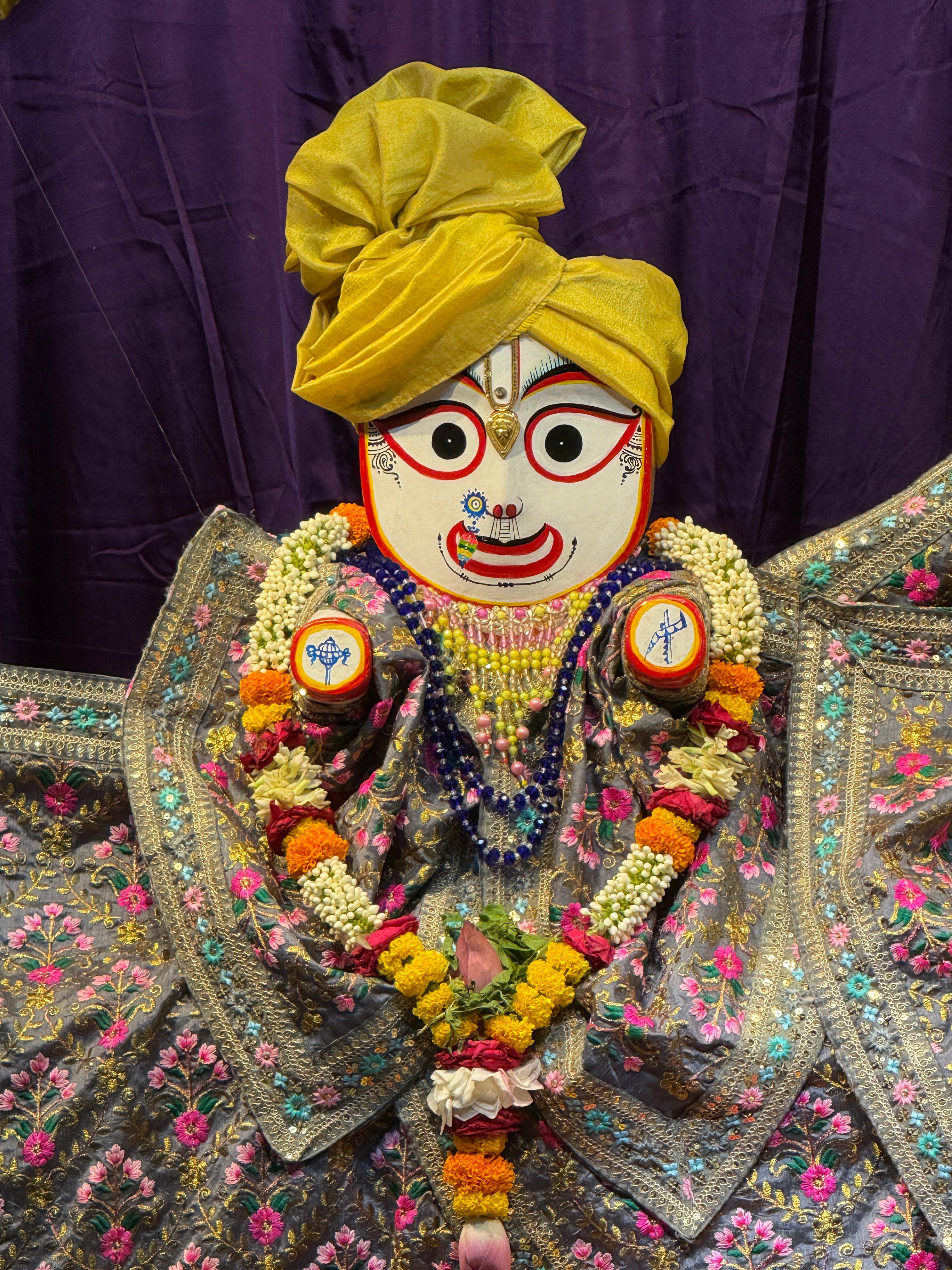 Decorated statue of an Indian deity with colorful attire and flowers.