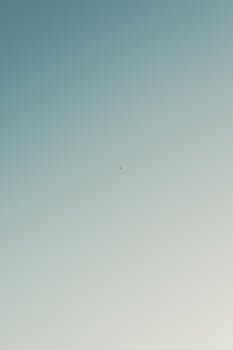 Minimalist photo of an airplane flying through a clear blue sky in Juárez, México.