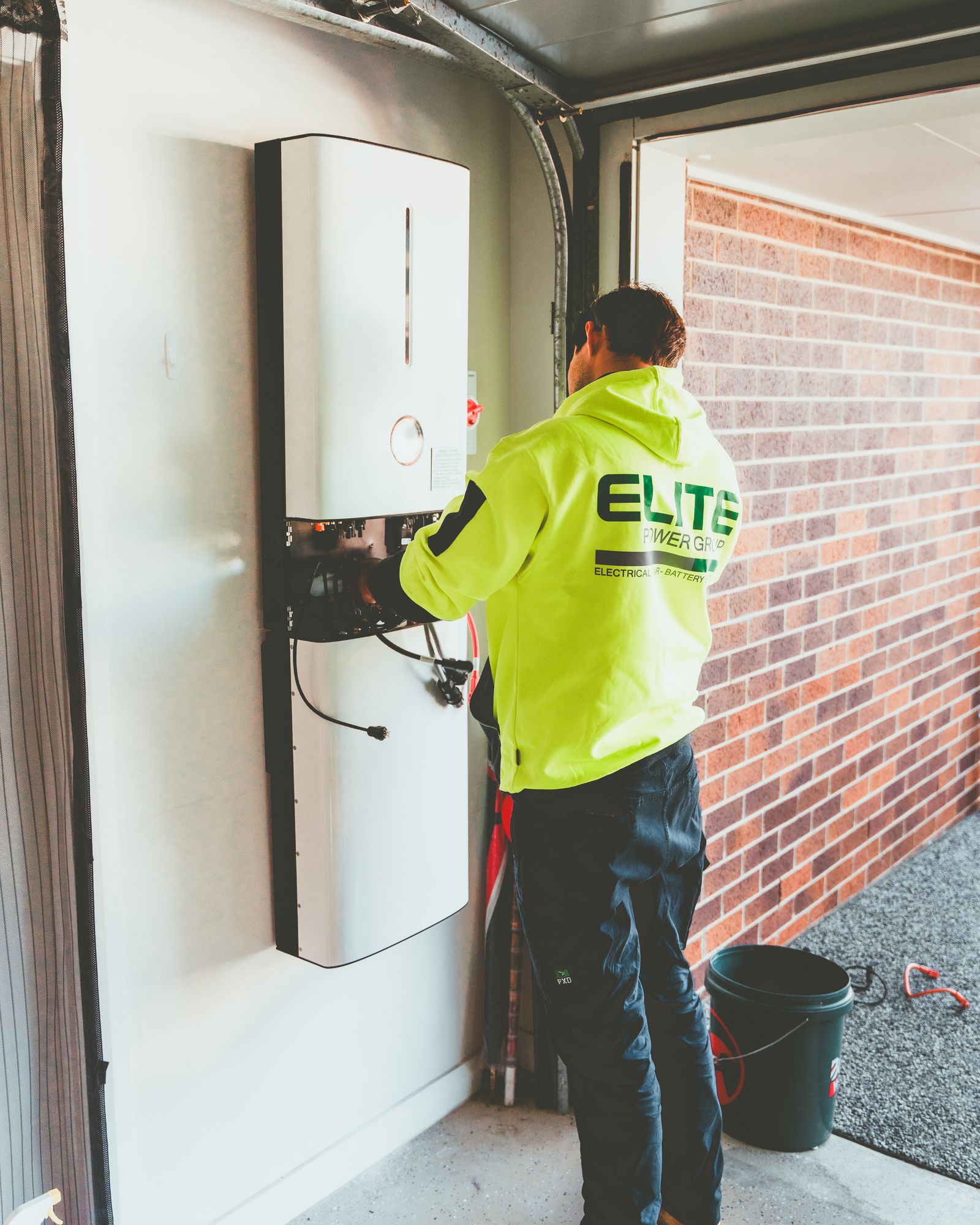 Electrician installing a wall-mounted solar inverter in a residential garage