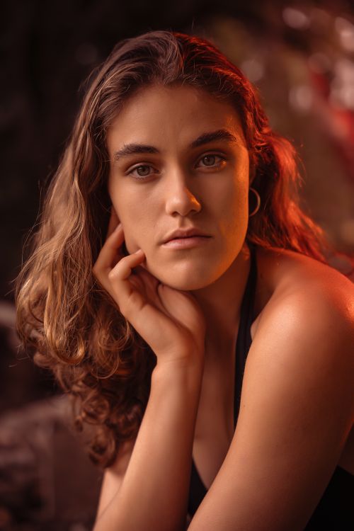 Free Artistic portrait of a woman with a soft expression under warm lighting. Stock Photo