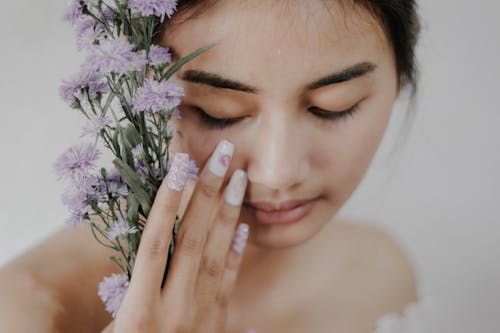 紫の花びらの花を持っている女性