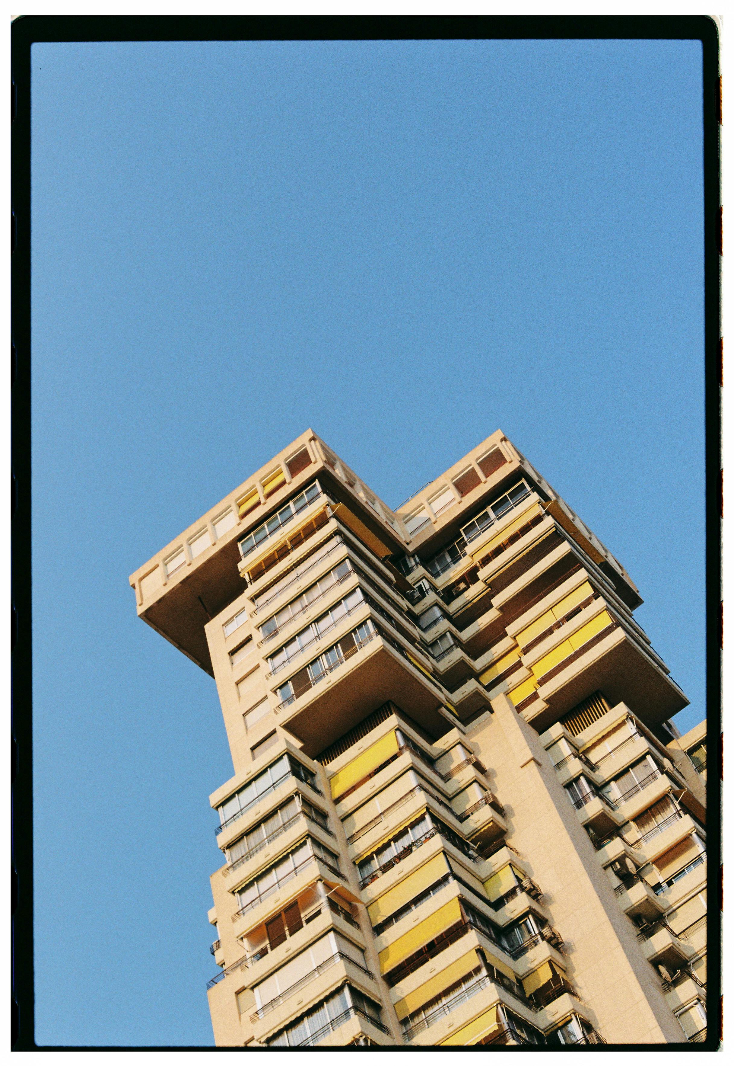 Striking architectural design of a high-rise building with distinct modular features under a clear blue sky.
