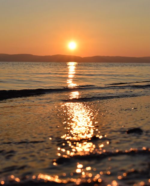 Free A mesmerizing sunset reflecting over calm sea waves, creating a serene coastal view. Stock Photo