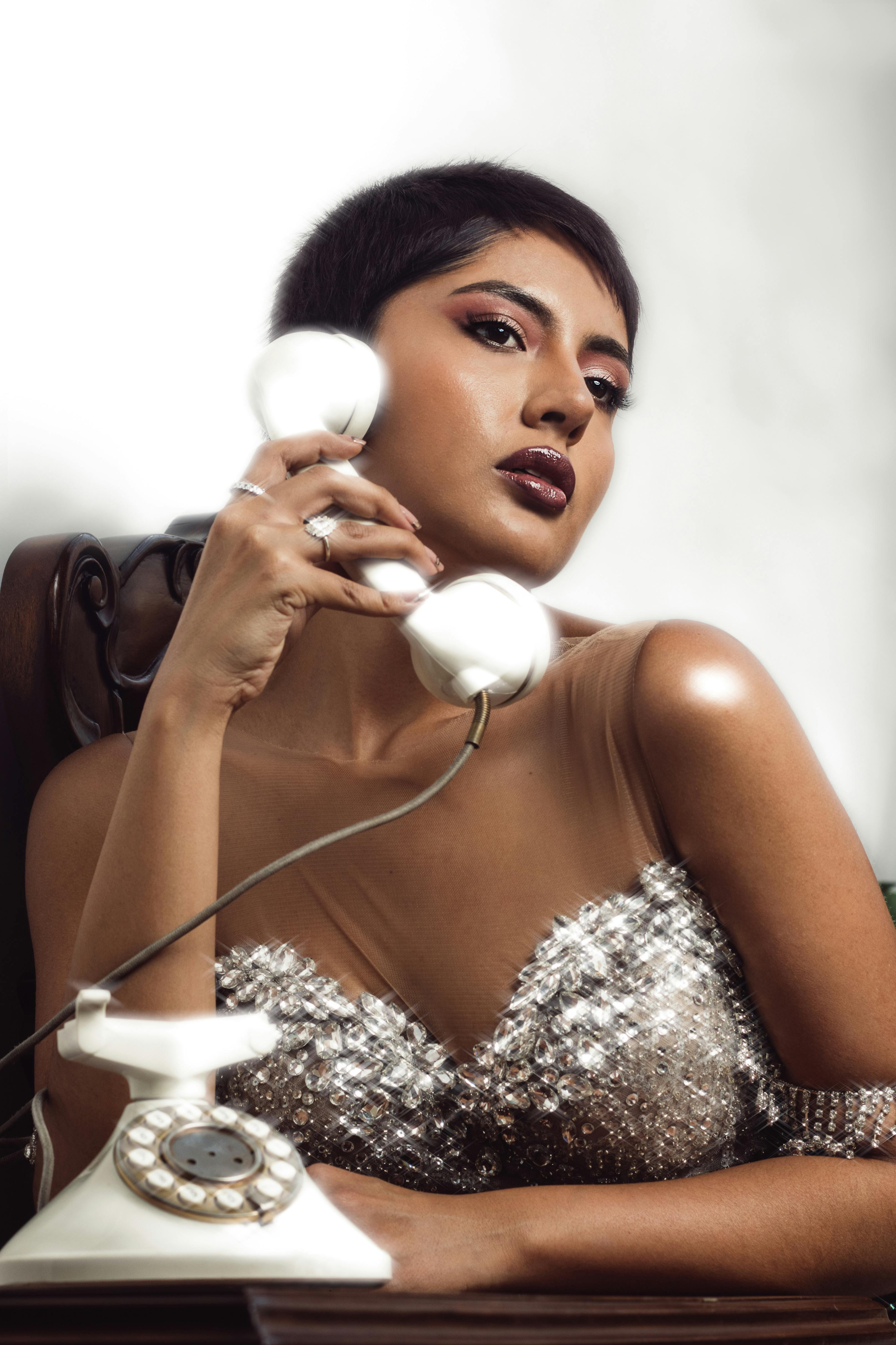 Kostenlos Elegante Frau in glamouröser Kleidung mit einem Retro-Telefon, das modernen Stil mit Vintage-Elementen verbindet. Stock-Foto