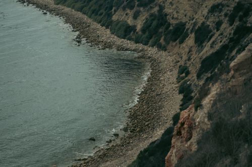 Free Aerial view of a rugged coastline with rocky shore and waves hitting the cliffs, capturing nature's raw beauty. Stock Photo
