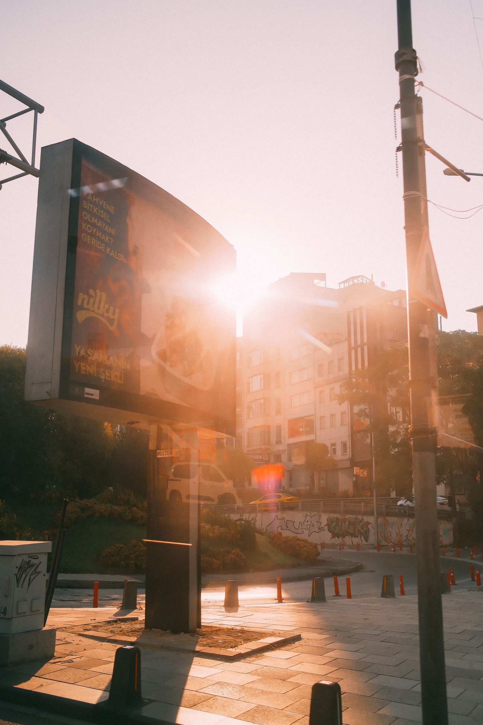 Backlit billboard above a city street at sunset
