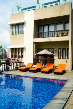Contemporary villa featuring a pool and vibrant orange loungers for a luxurious retreat.