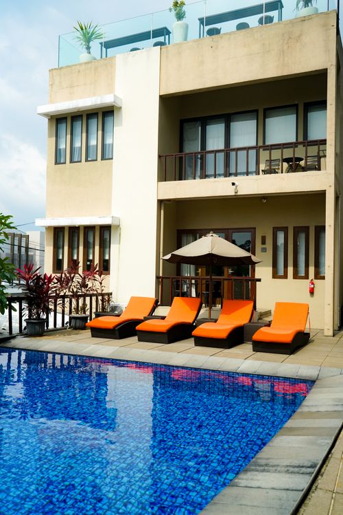Free Contemporary villa featuring a pool and vibrant orange loungers for a luxurious retreat. Stock Photo