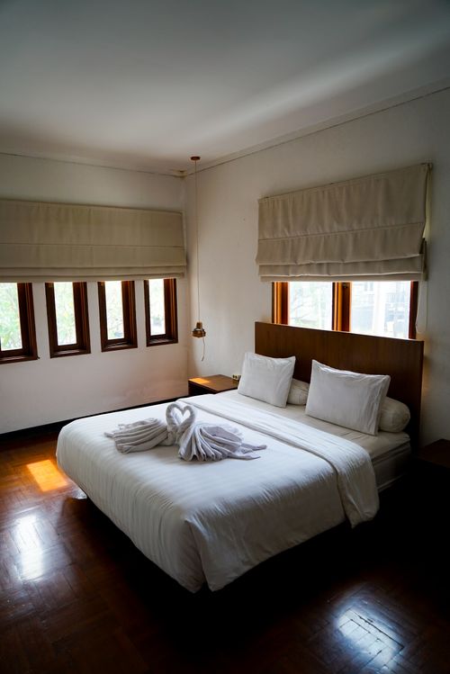 Free Elegant bedroom with swan towel art and soft lighting offers a warm, inviting atmosphere. Stock Photo