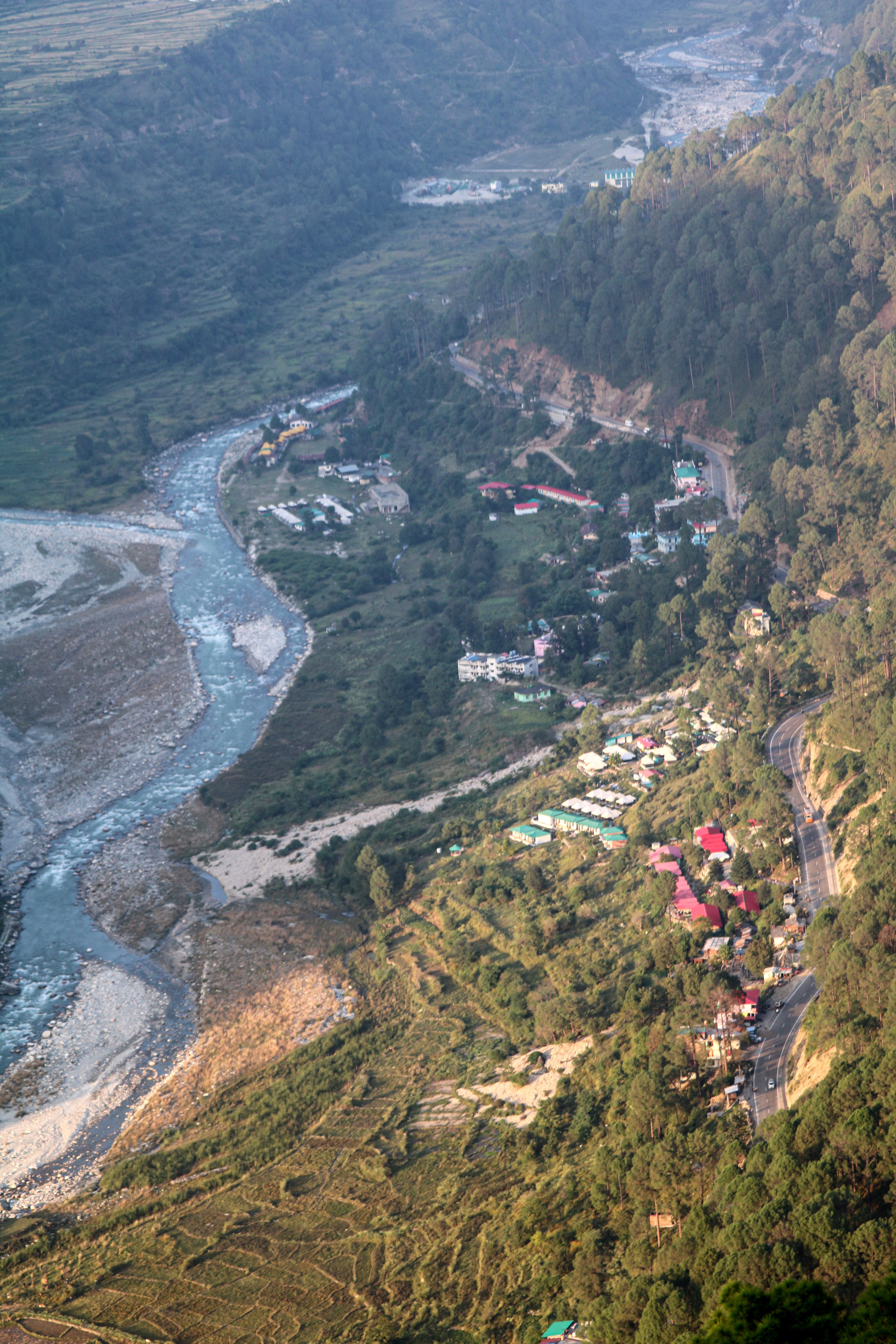 A breathtaking aerial shot of a lush valley with a river and forested mountains in Uttarakhand, India.