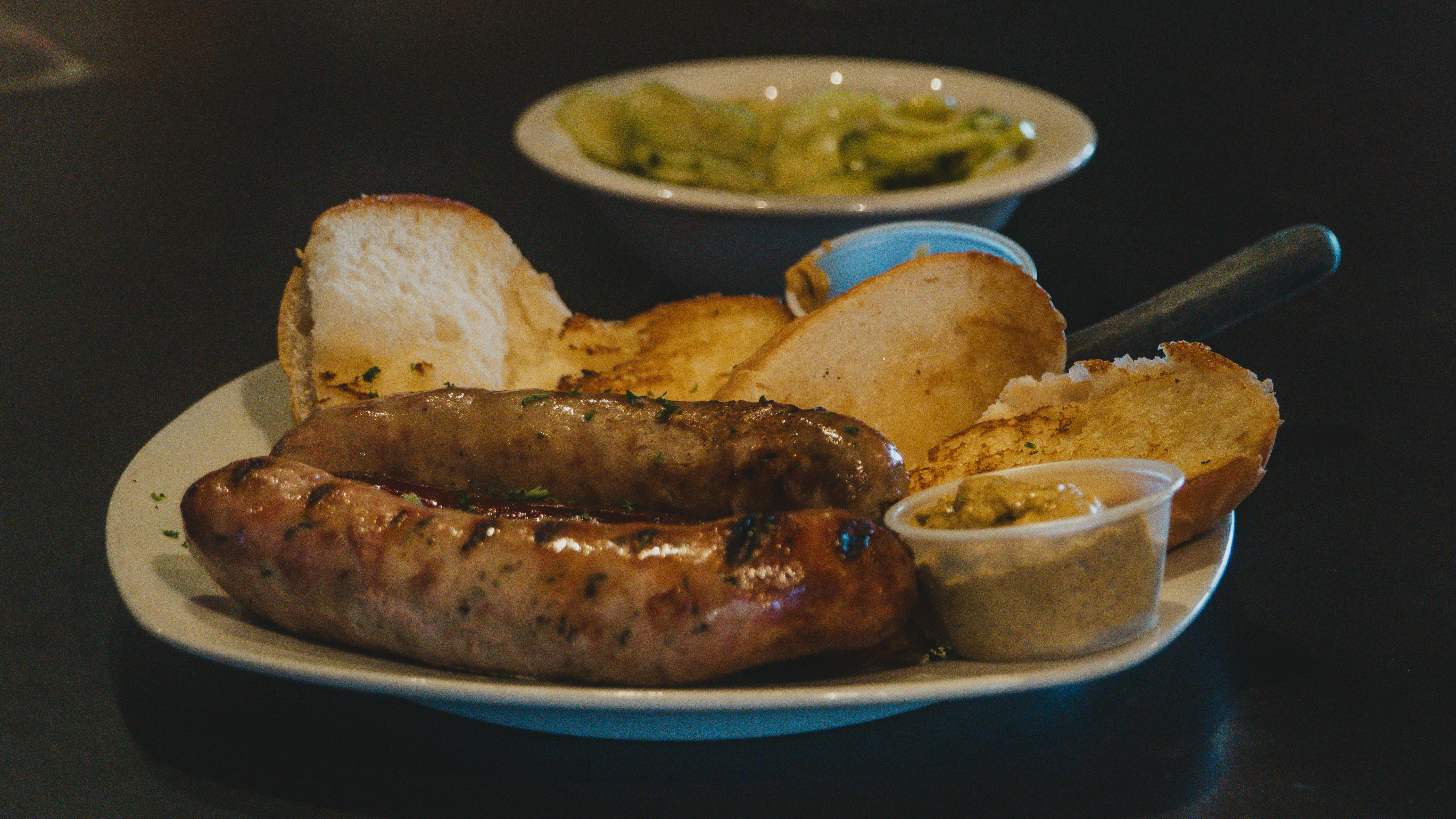Plate of grilled sausages served with bread and mustard, perfect for a cozy meal.