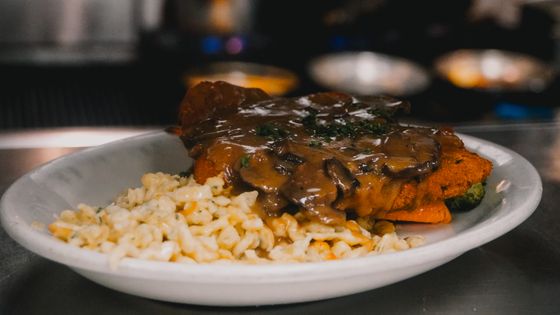 Breaded pork schnitzel smothered in mushroom gravy over buttered spaetzle on a white plate