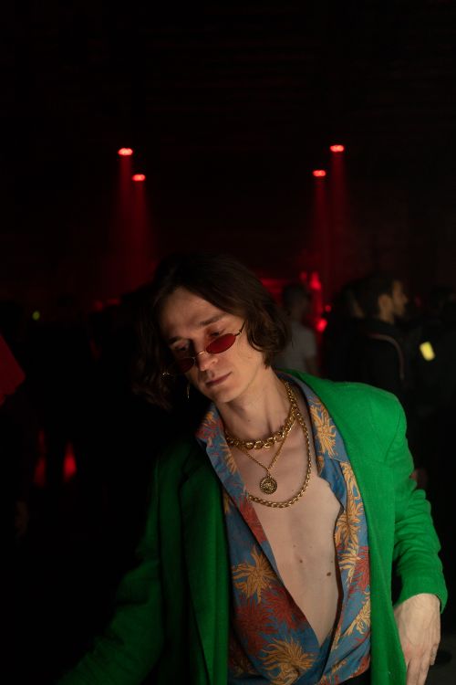 Free Fashionable man with sunglasses and gold chains in a dark nightclub setting. Stock Photo