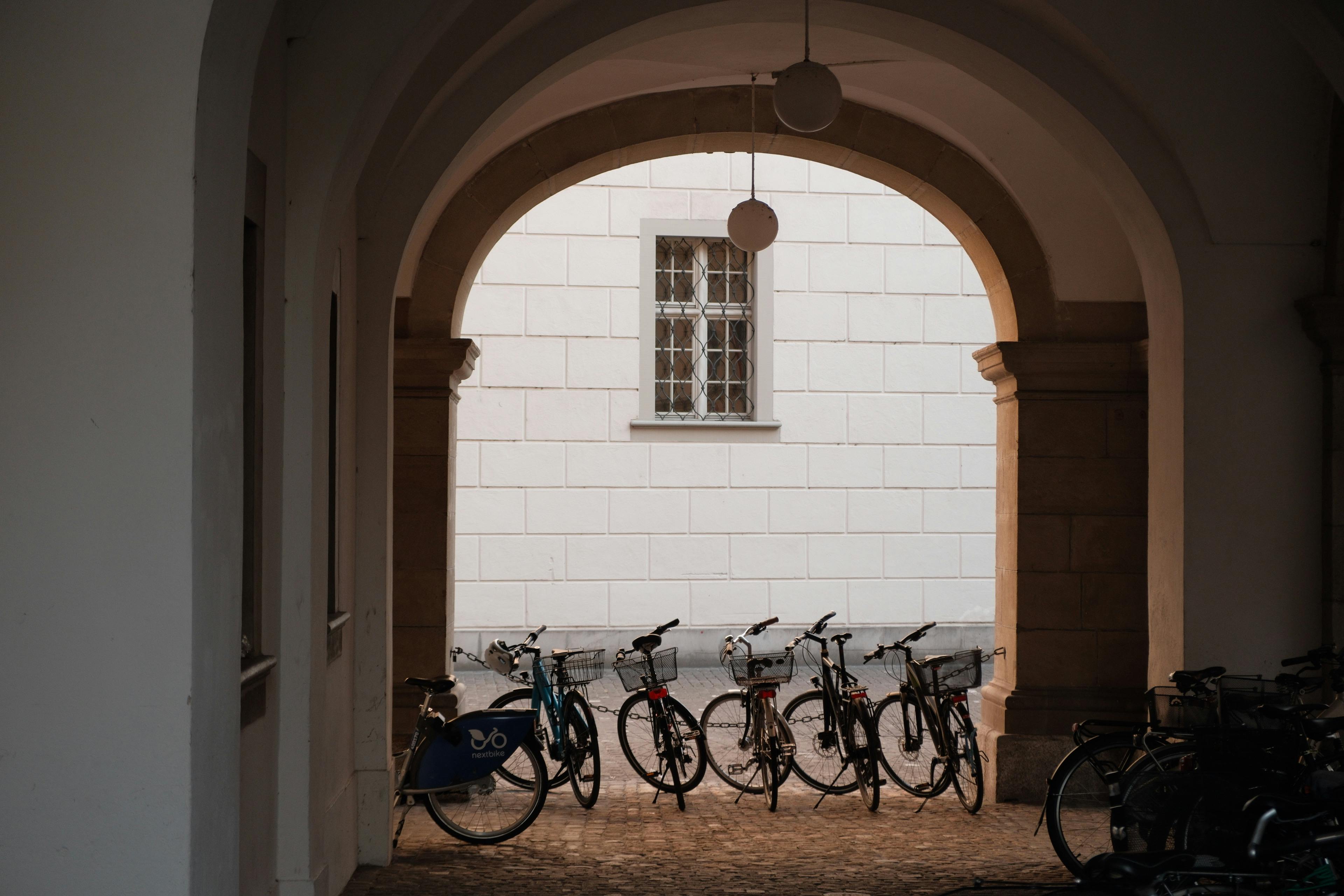 A row of bicycles parked under an elegant archway in Zürich. Perfect for urban and architectural themes.