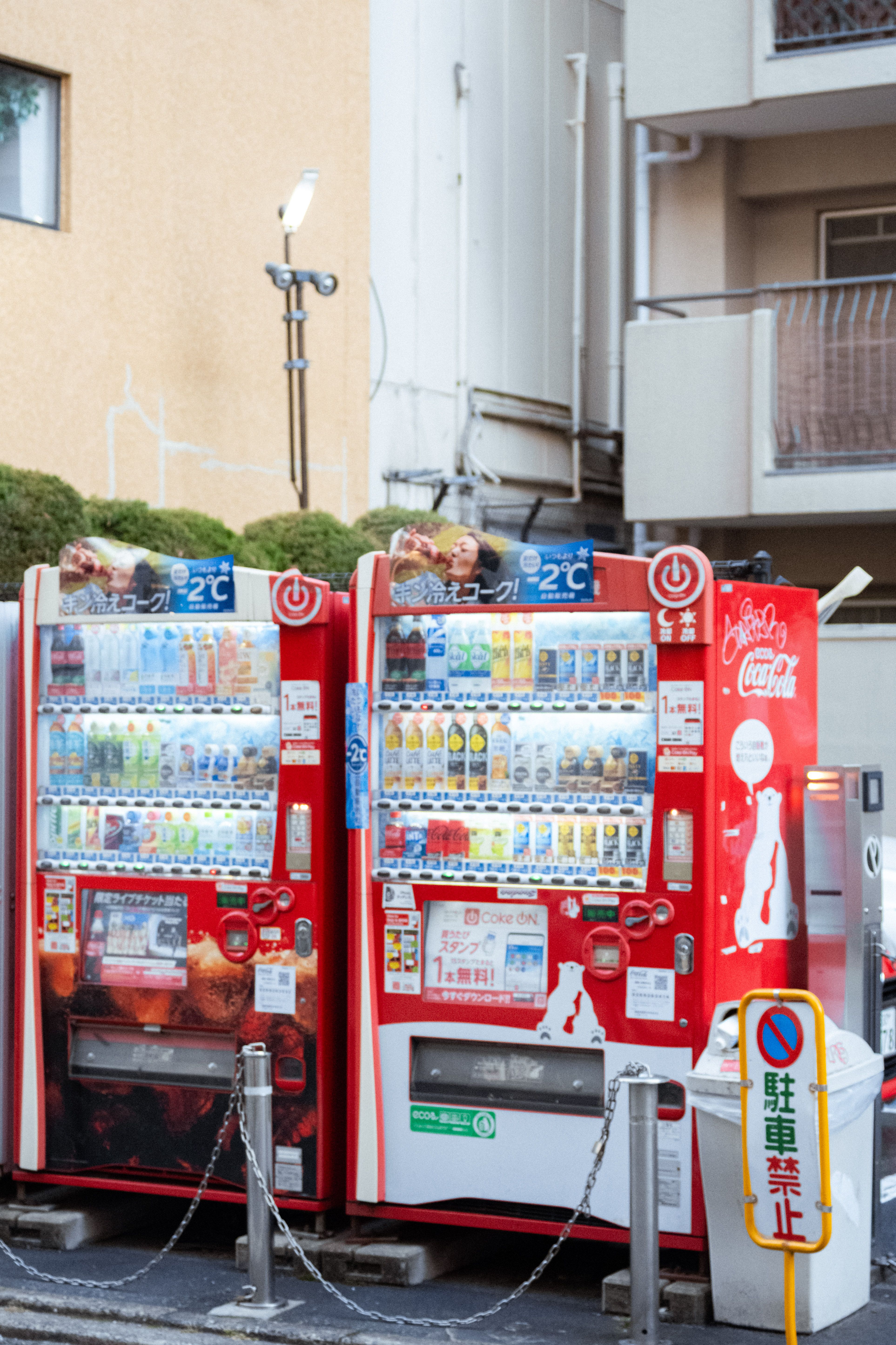 Two red vending machines with beverages on a city street, Japan.
