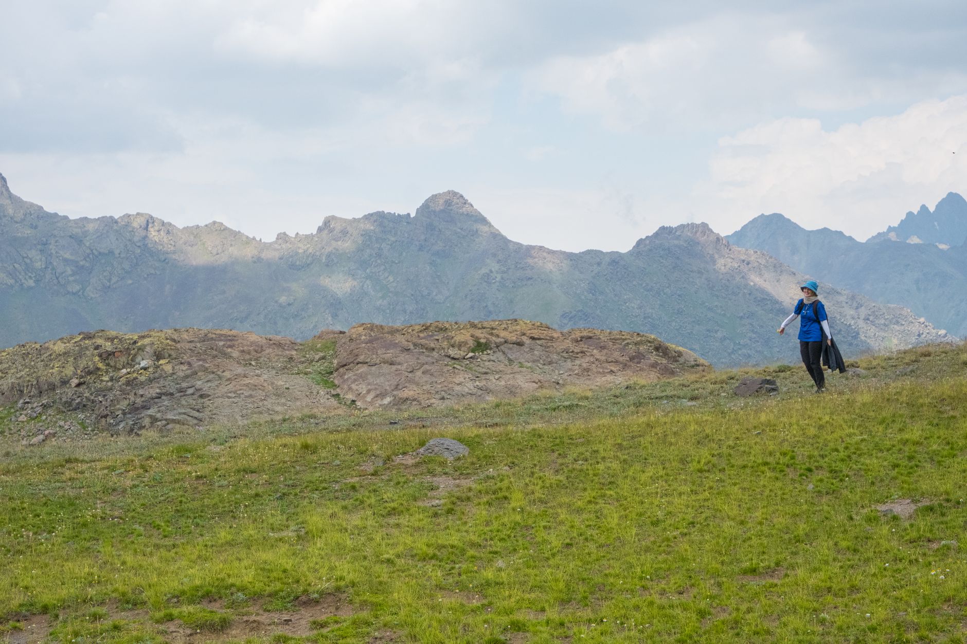 A lone hiker on an alpine trail, the path ahead clearly marked