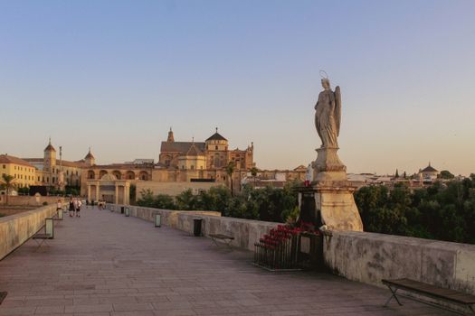 Scenic sunset view of the Roman Bridge, Córdoba with historic architecture in the background.