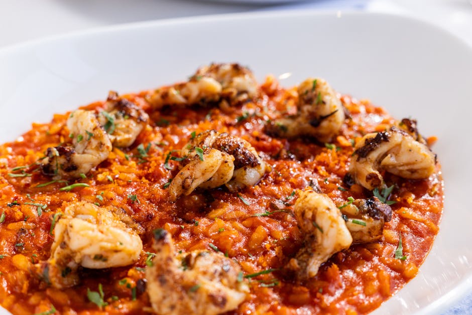 Flavorful risotto topped with grilled shrimp in a vibrant red sauce, perfect for seafood lovers.