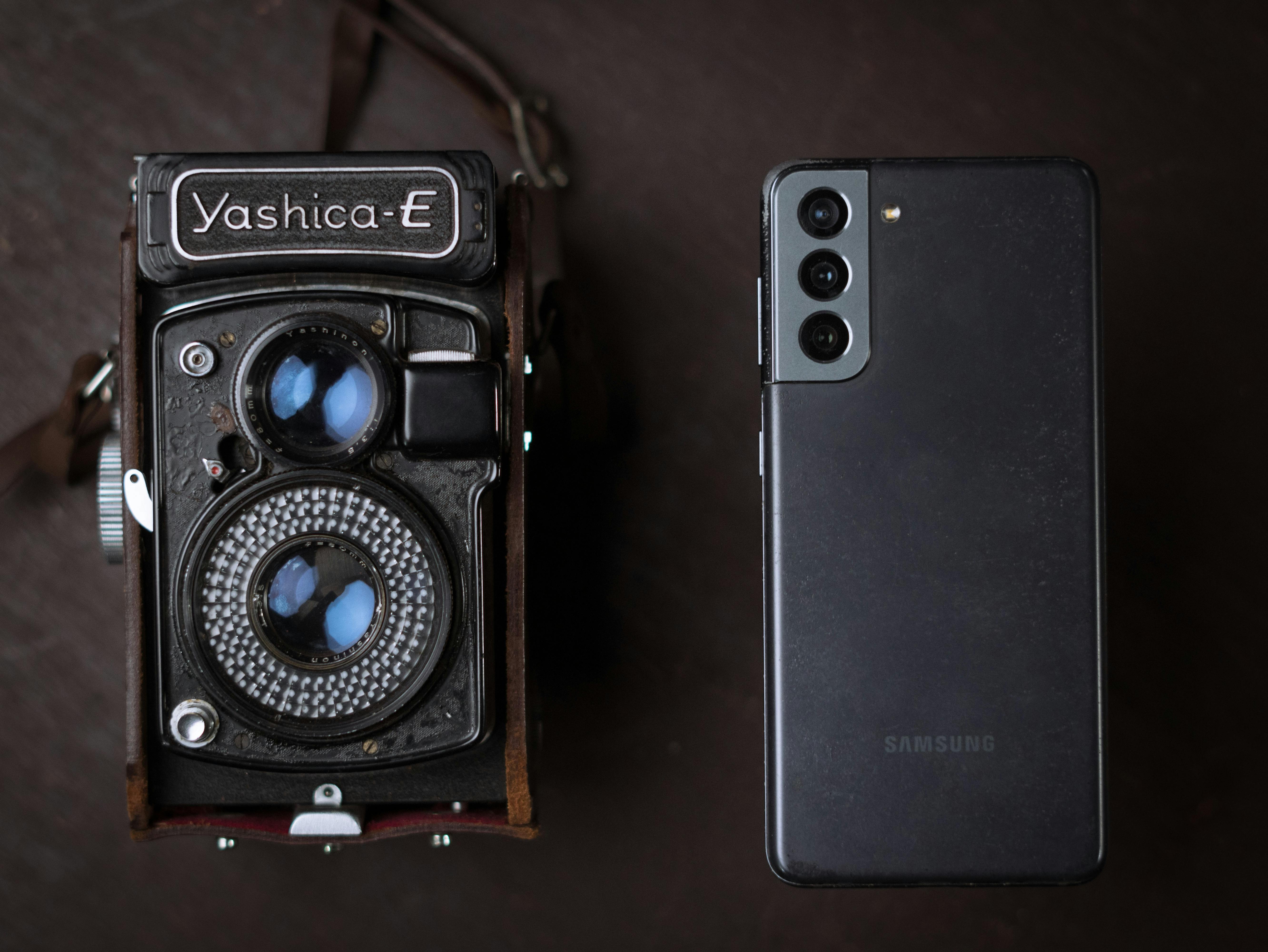 Een vintage Yashica camera naast een moderne smartphone, die oude en nieuwe technologie toont.
