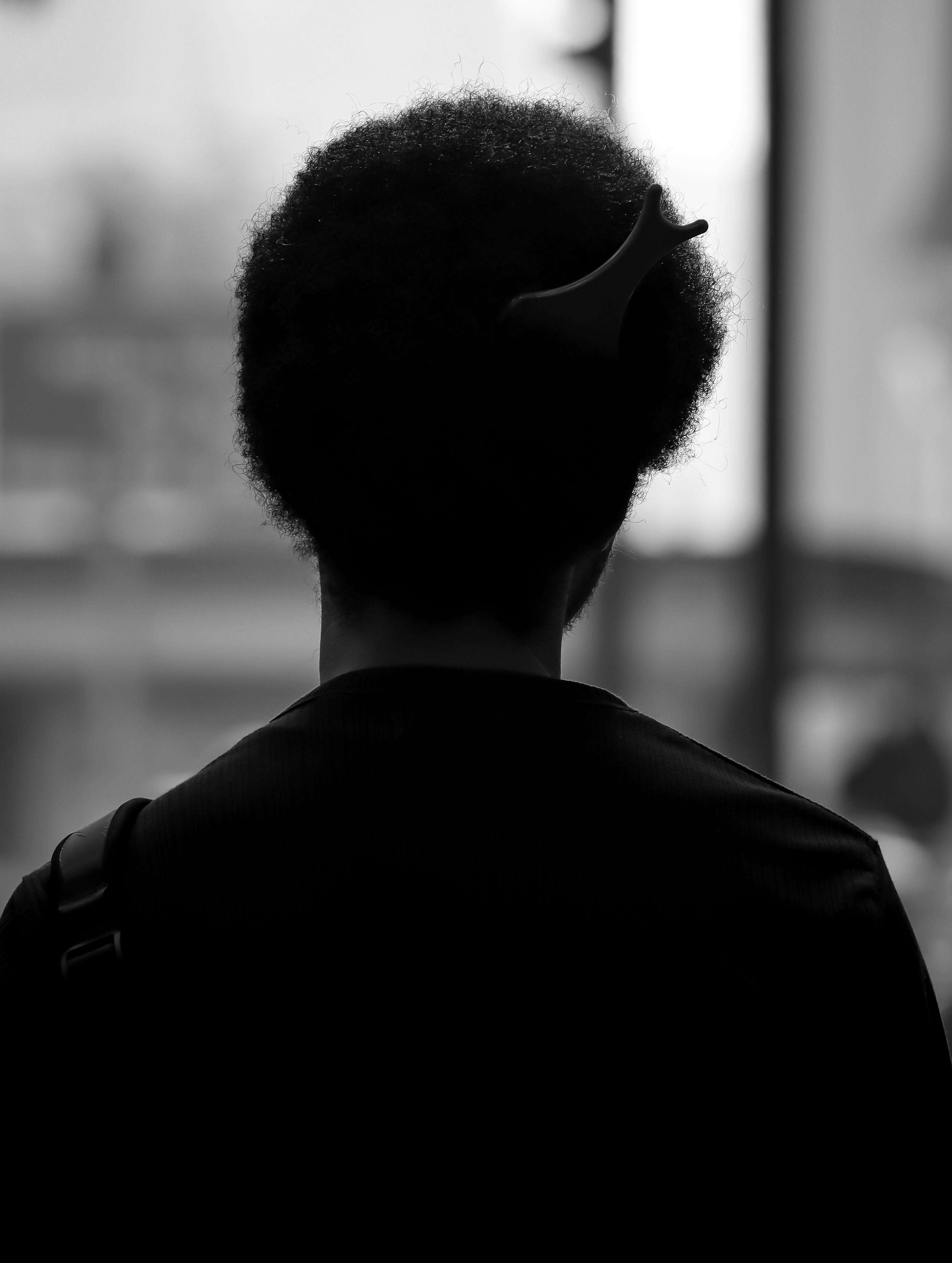 ingyenes Egy afro hajú személy fekete-fehér sziluettje városi környezetben titokzatos hangulatot teremt. Stockfotó