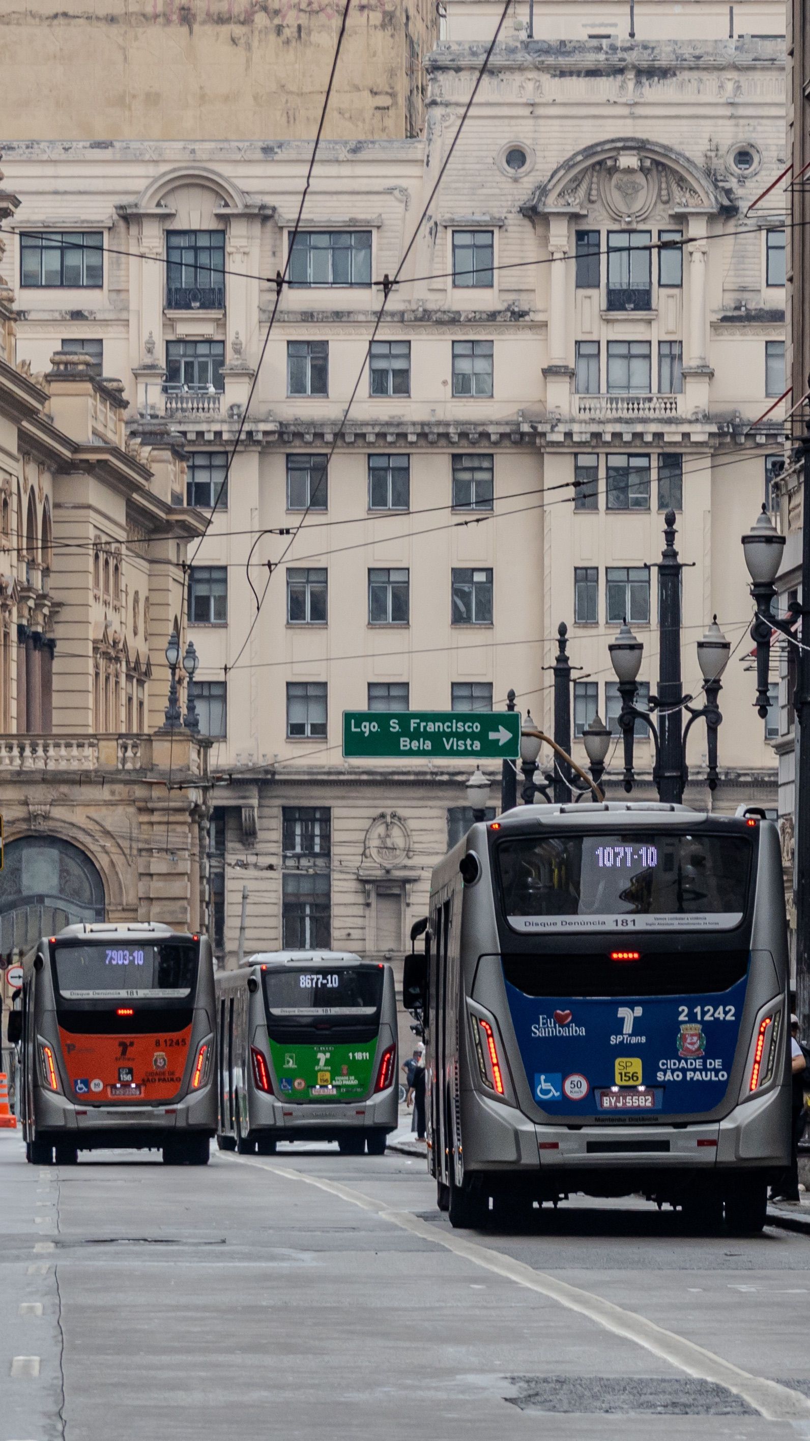 Three modern buses on a historic street of São Paulo, Brazil, showcasing urban transit.