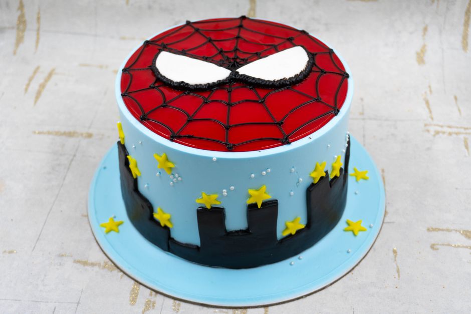 Vibrant Spider-Man themed cake featuring web design and cityscape for birthdays or events.