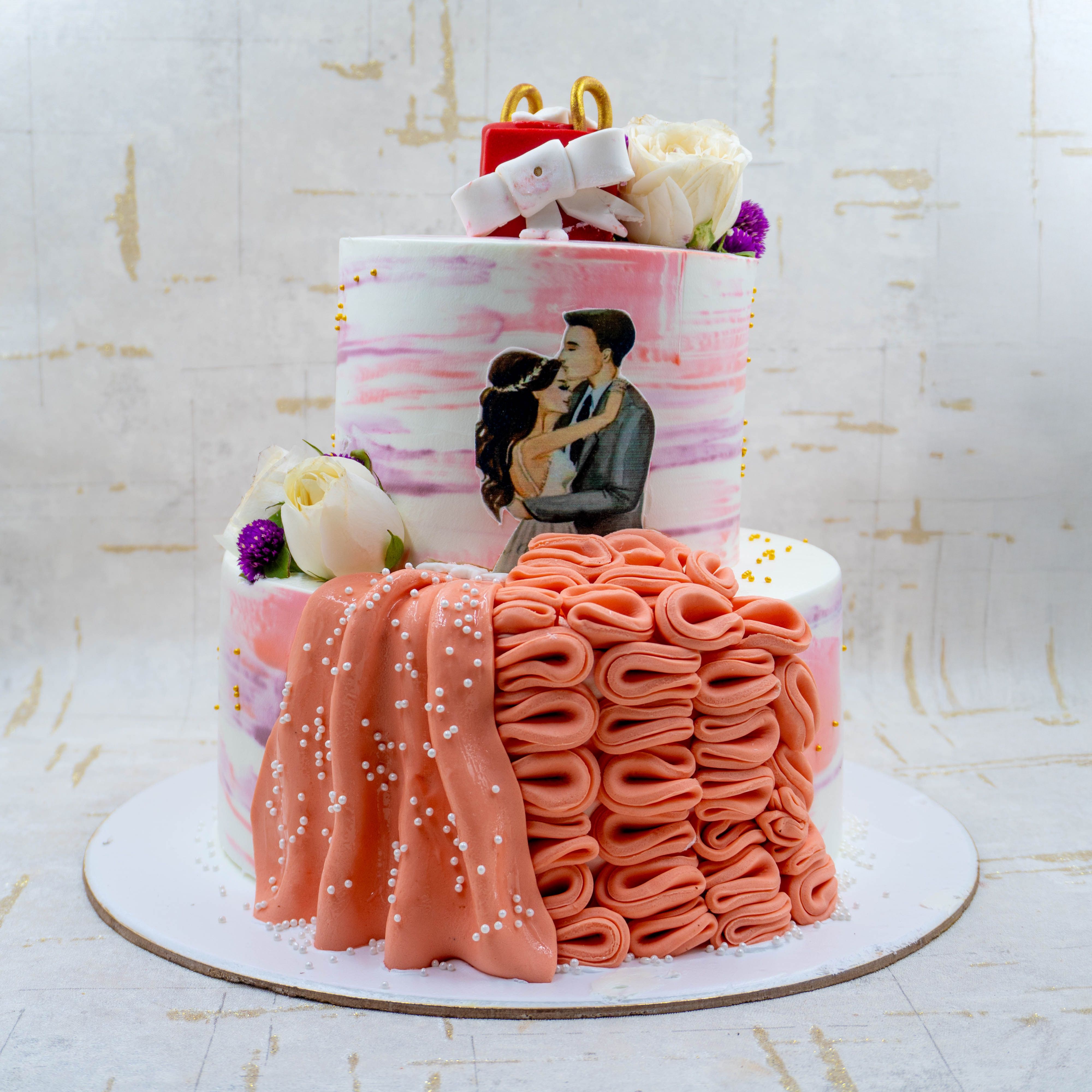 A beautifully decorated wedding cake featuring floral elements and a painted couple in embrace.