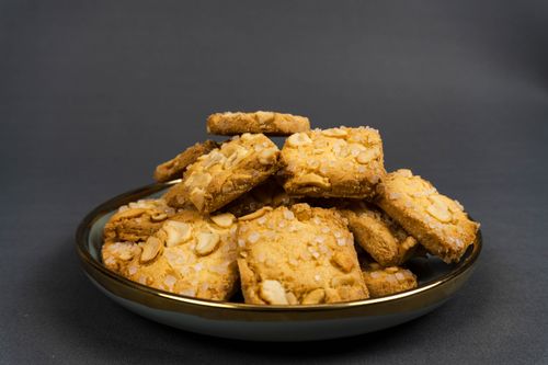 Free Appetizing almond cookies piled on an elegant plate, perfect for a cozy treat. Stock Photo