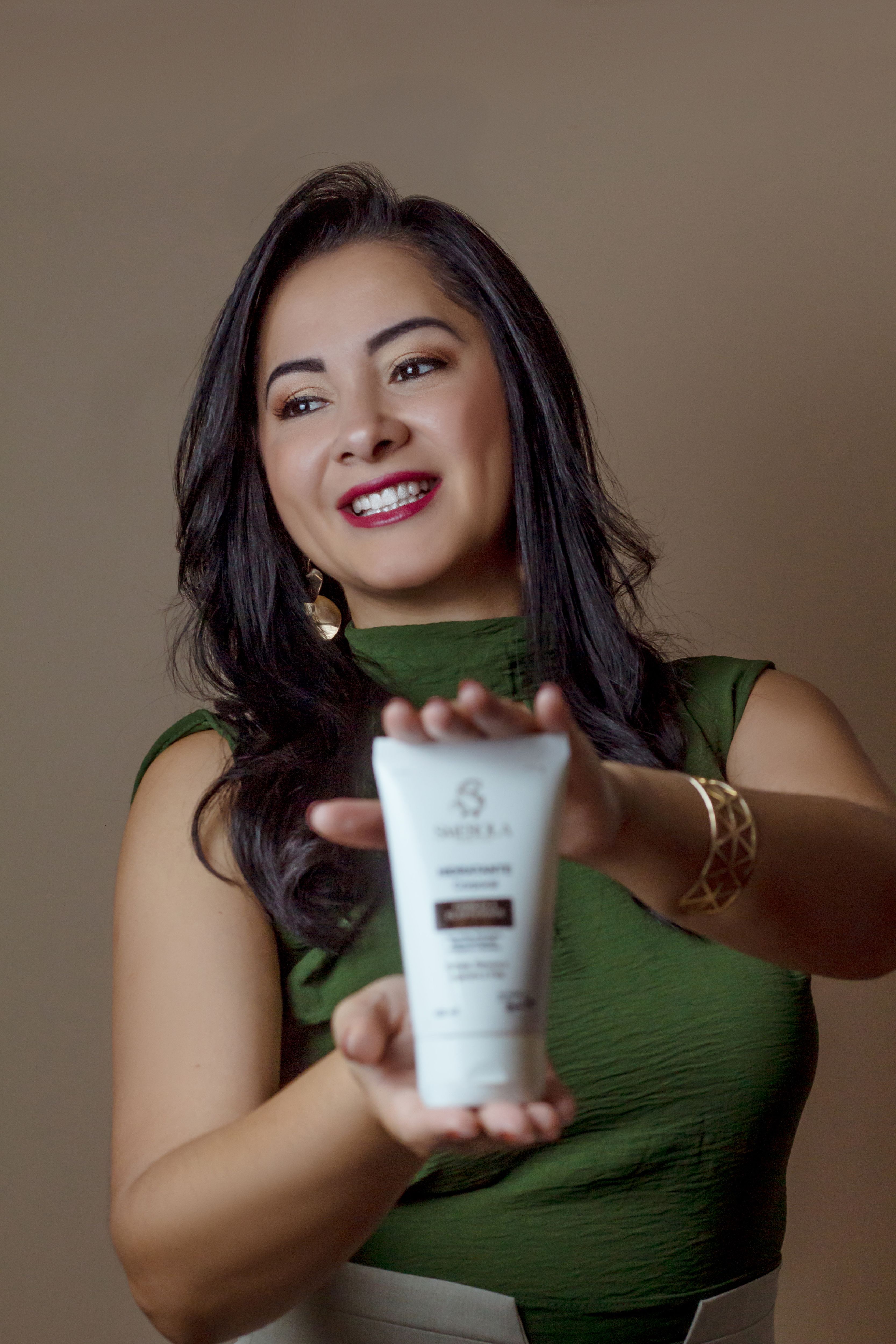 Smiling woman showcasing a hair care product, highlighting beauty and style.