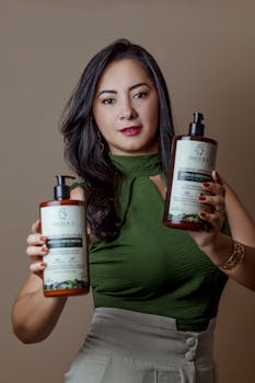 Woman in green top holding two hair care products, presenting them with a smile.