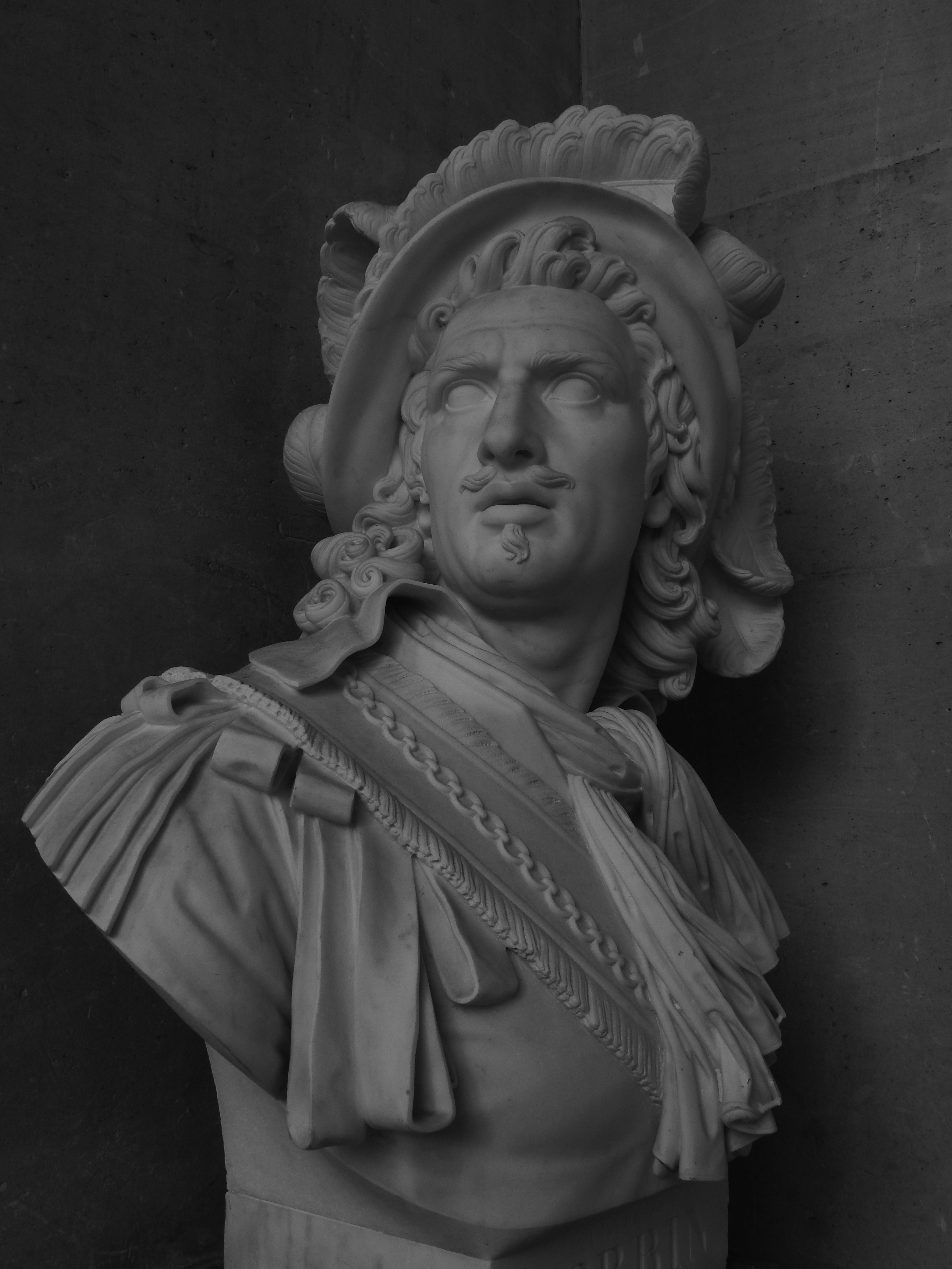 A monochrome marble bust with intricate details in a dramatic light setting.