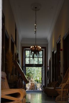 Elegant corridor with chandelier lighting in a stylish indoor space featuring wicker decor.