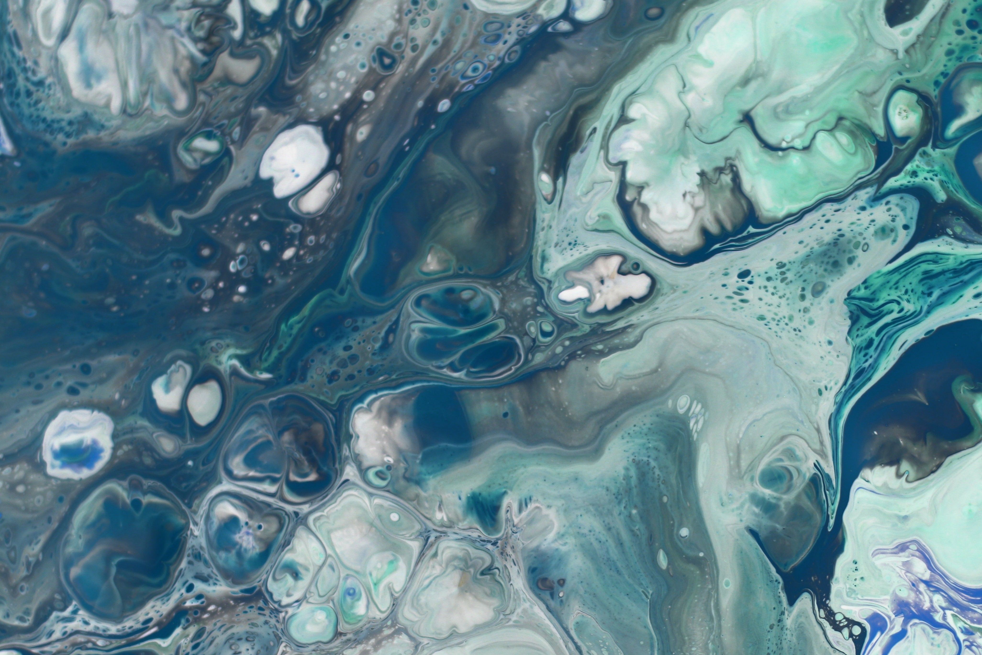Vibrant abstract fluid art with teal, white, and blue swirls resembling ocean waves.