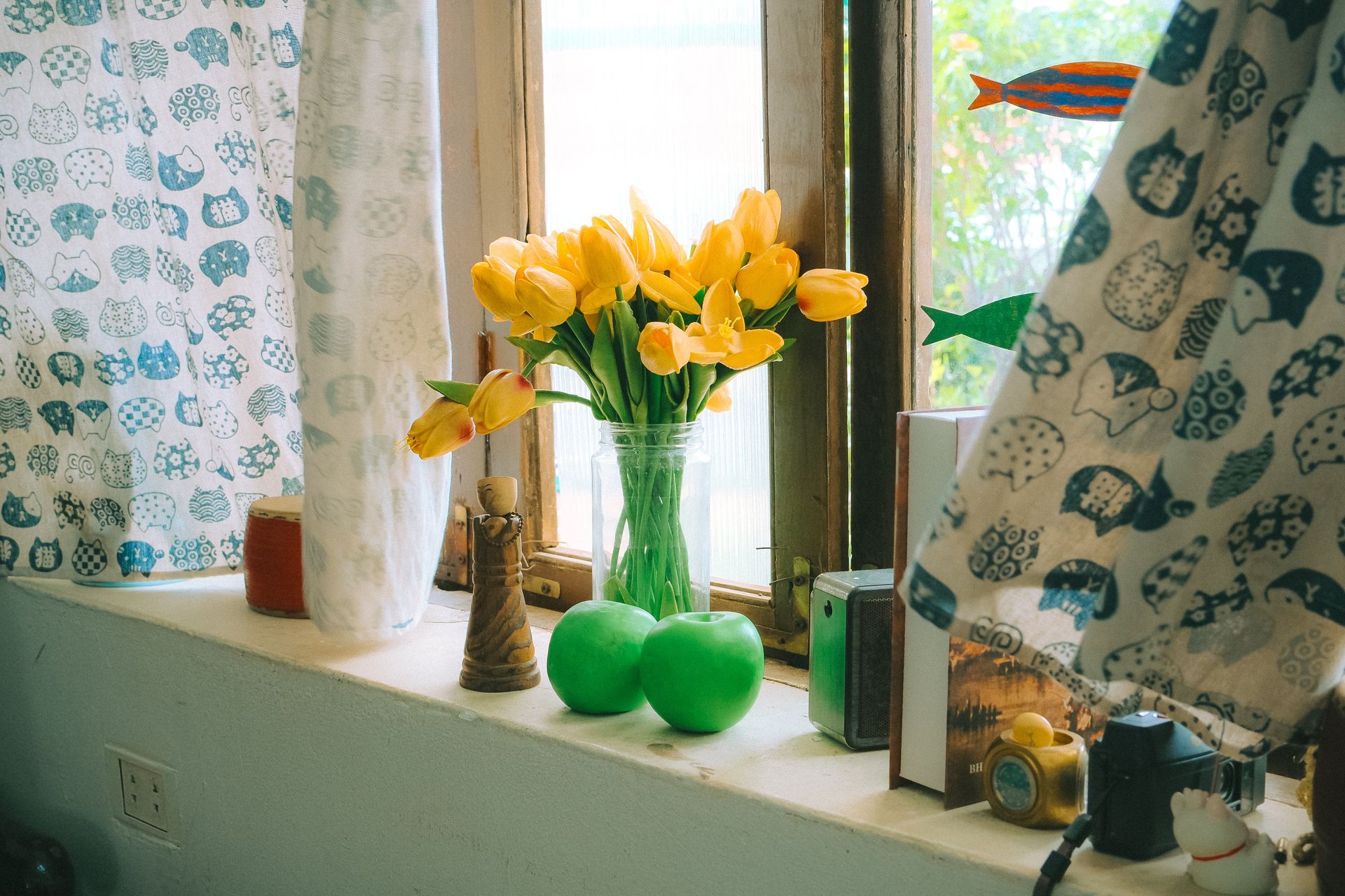 A charming indoor scene featuring yellow tulips, decor items, and a sunlit window sill.