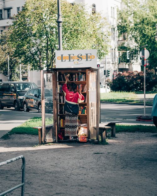 Free A person browsing books at a street library in Kreuzberg, Berlin on a sunny day. Stock Photo