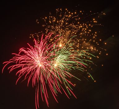 Colorful fireworks burst in the night sky, creating an exciting and festive atmosphere.