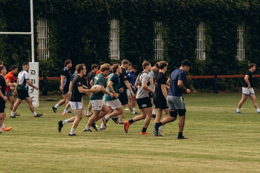 A group of young men practicing rugby on a lush field in Dublin, Ireland.