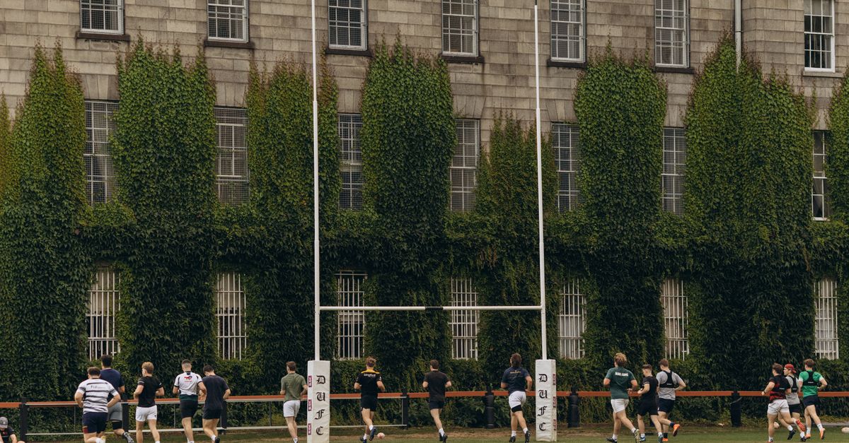 Rugby players practice on lush grounds of Trinity College Dublin.
