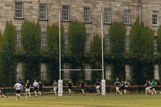 Rugby players practice on lush grounds of Trinity College Dublin.